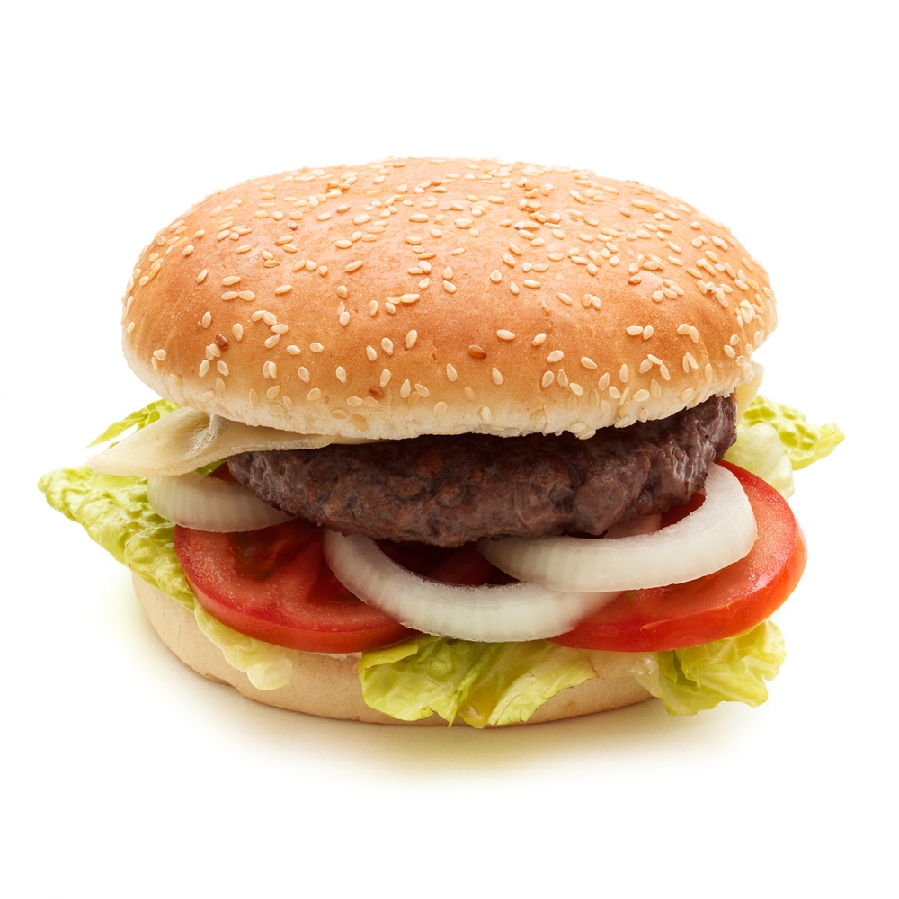 Imagen en la que se ve un panecillo redondo con una hamburguesa dentro y guarnición de lechuga, tomate y cebolla