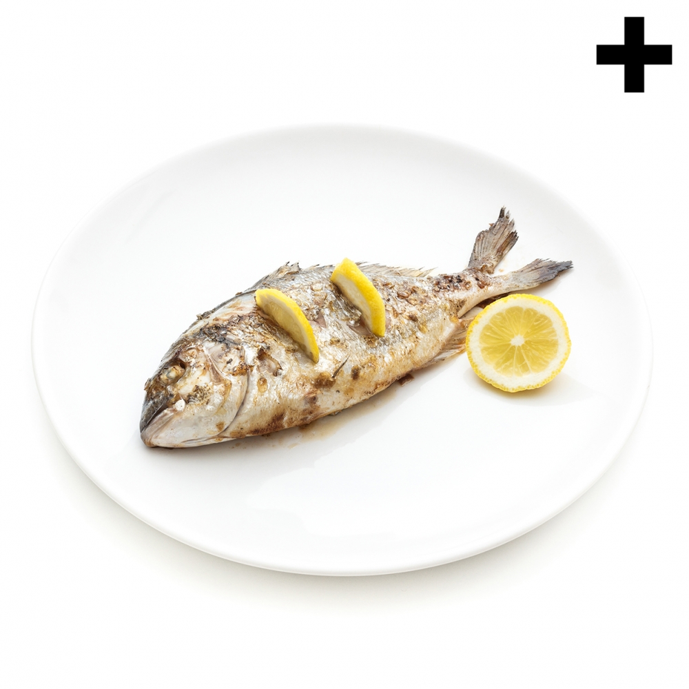 Imagen en la que se ve un pescado cocinado con limón sobre un plato