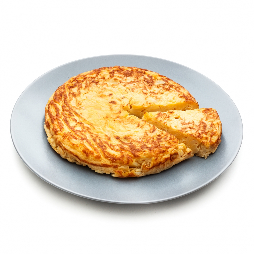Imagen en la que se ve un plato con una tortilla de patata entera a la que se le ha cortado un trozo que sobresale ligeramente de la tortilla