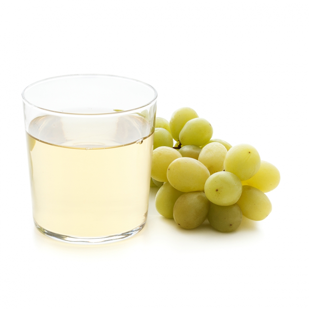 Imagen en la que se ve un vaso con zumo de uva y, a su lado, un racimo de uvas