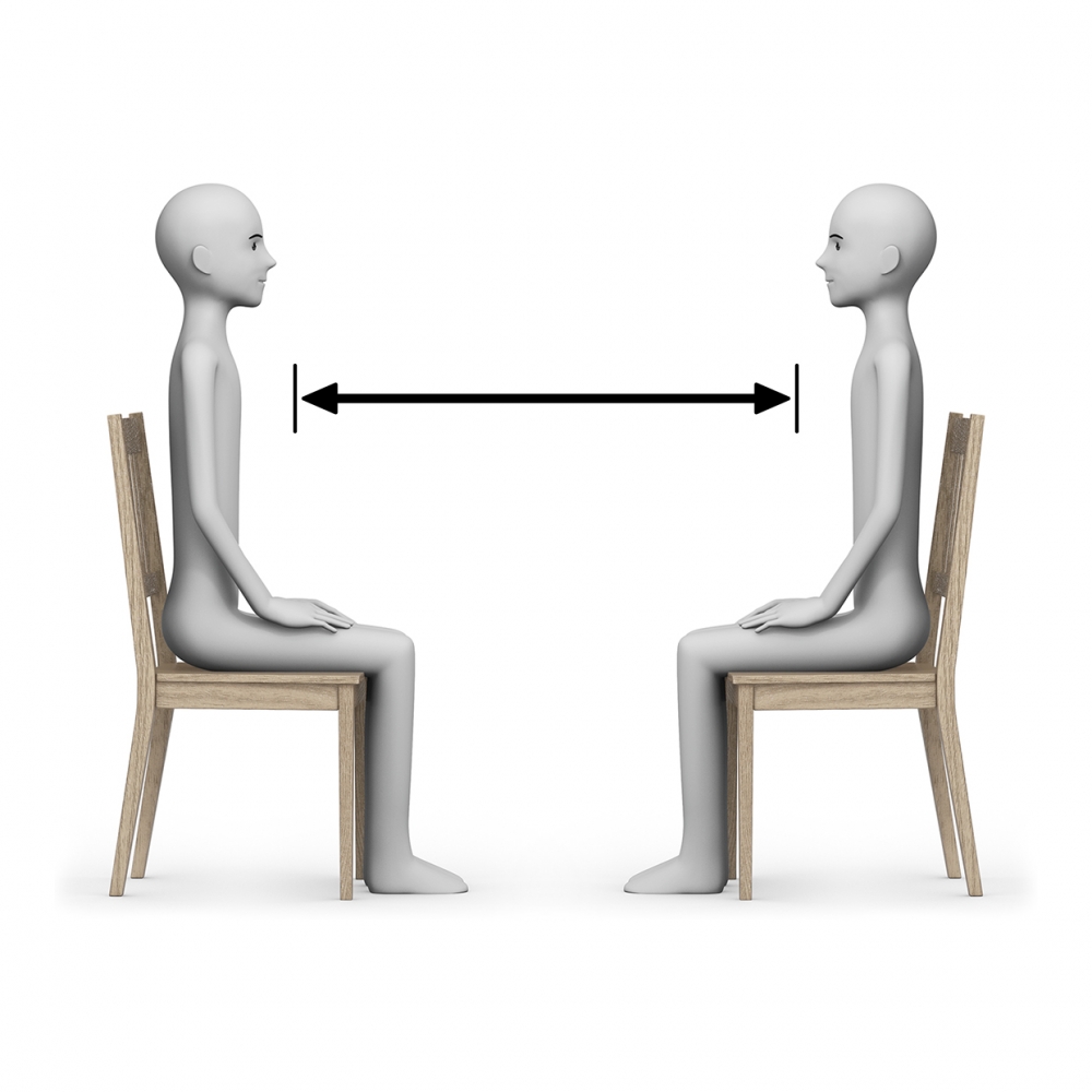 Dos personas están sentadas guardando la distancia de seguridad