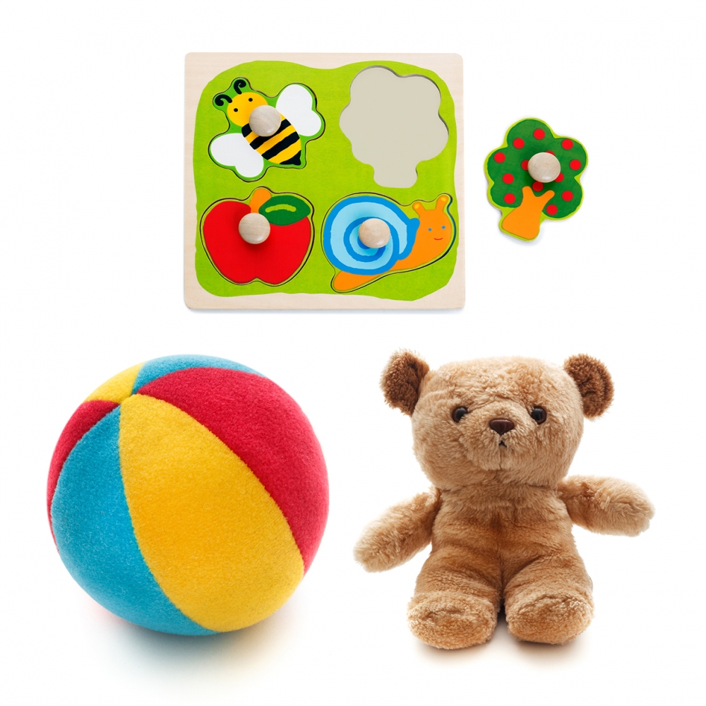 Imagen en la que se ven tres juguetes: una pelota de espuma, un osito y encajables