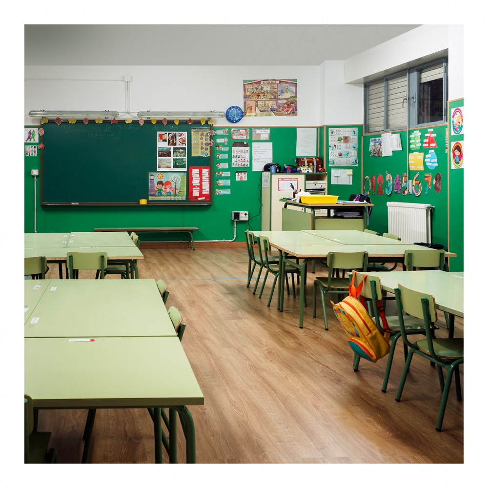 Imagen en la que se ve una clase compuesta por mesas, sillas y una pizarra al fondo