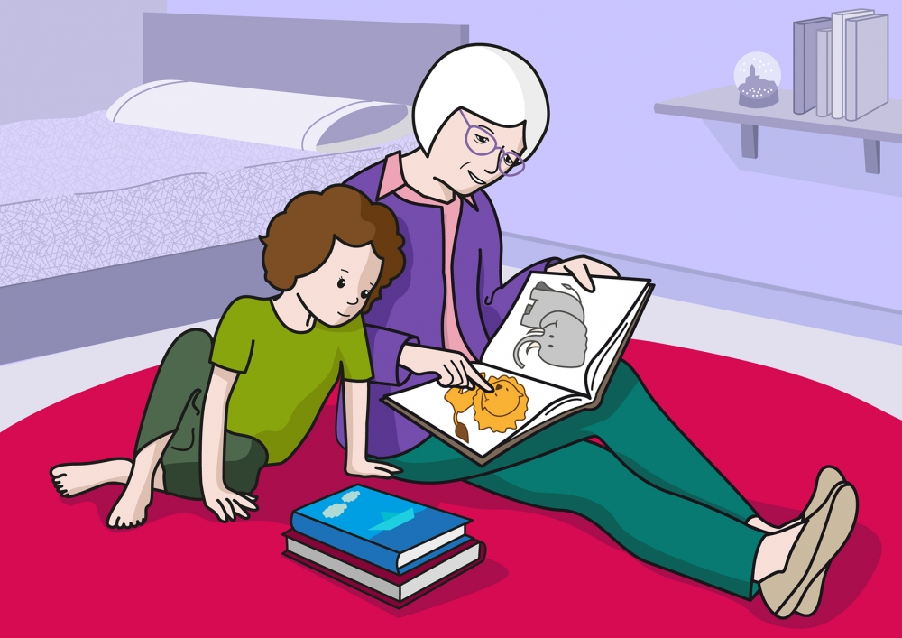 En la escena, se observa a una persona mayor leyendo un cuento a una niña, sentadas en la alfombra.