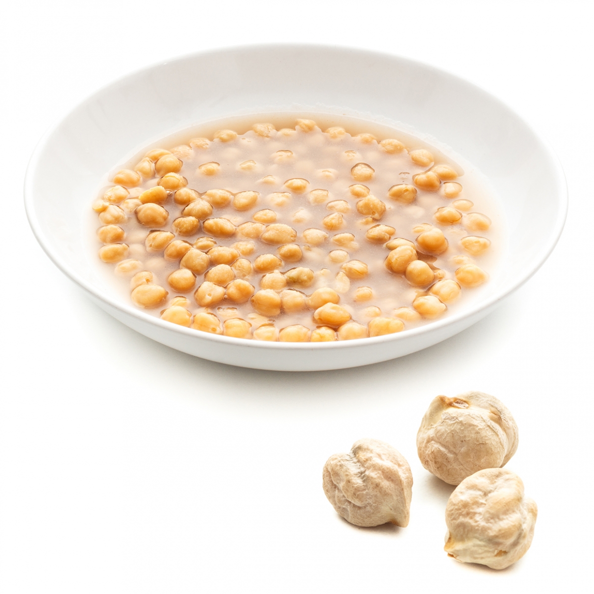 Imagen en la que se ve un plato de garbanzos cocinados y tres garbanzos crudos delante del plato