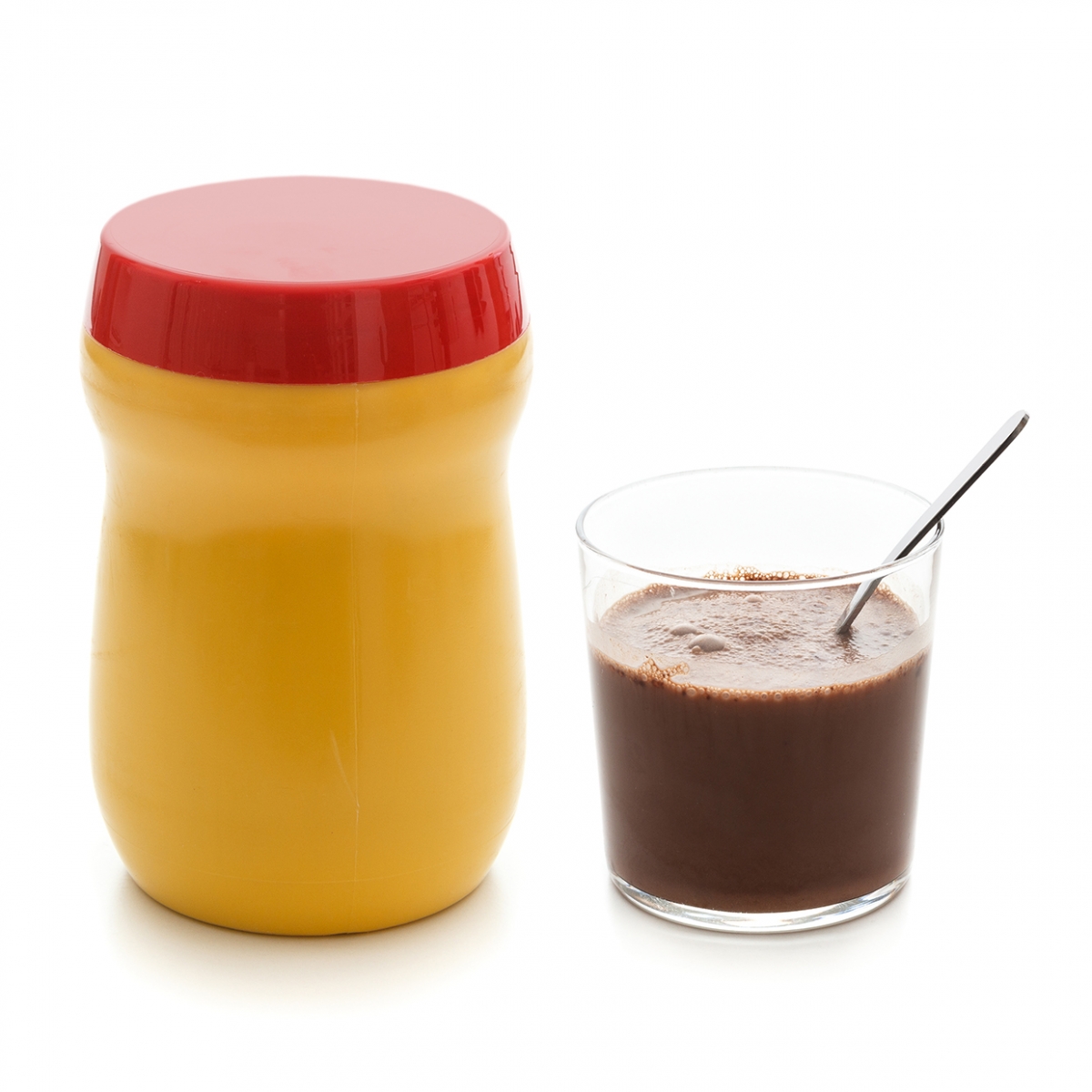 Imagen en la que se ve un bote de cacao con un vaso a su lado con cacao y una cucharilla en su interior