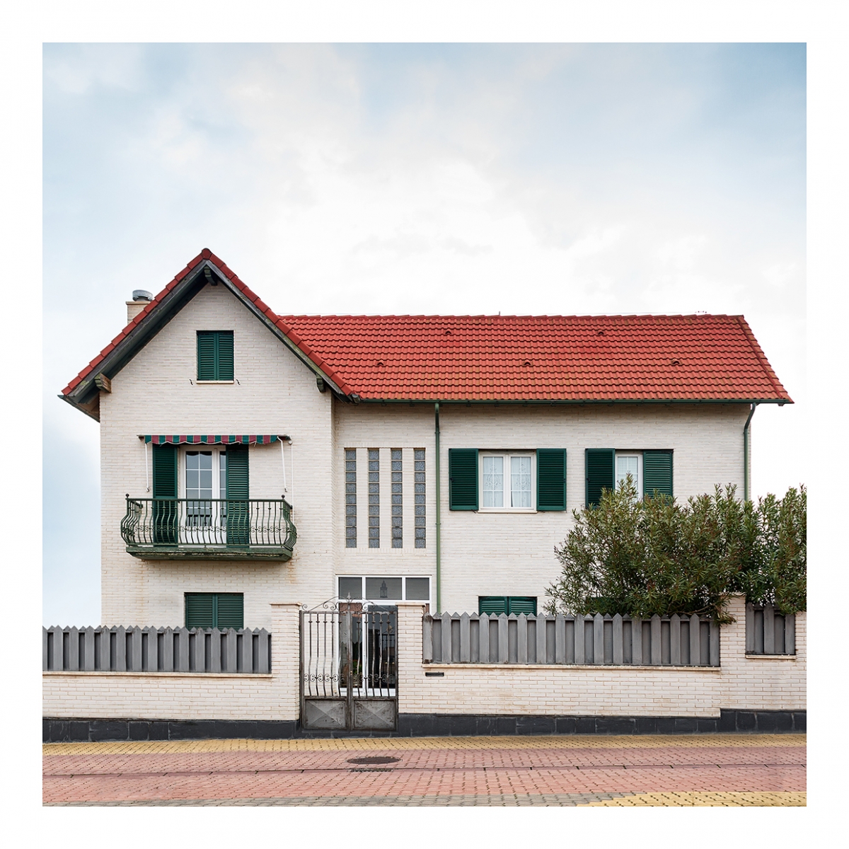 Imagen en la que se ve una casa de dos plantas y ático con una valla en el frente