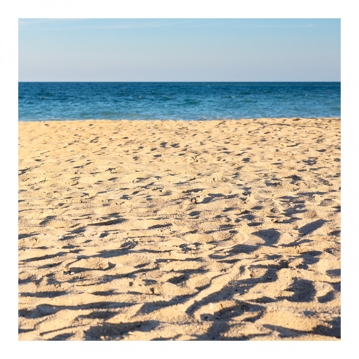 Imagen en la que se ve una playa de arena con el mar al fondo
