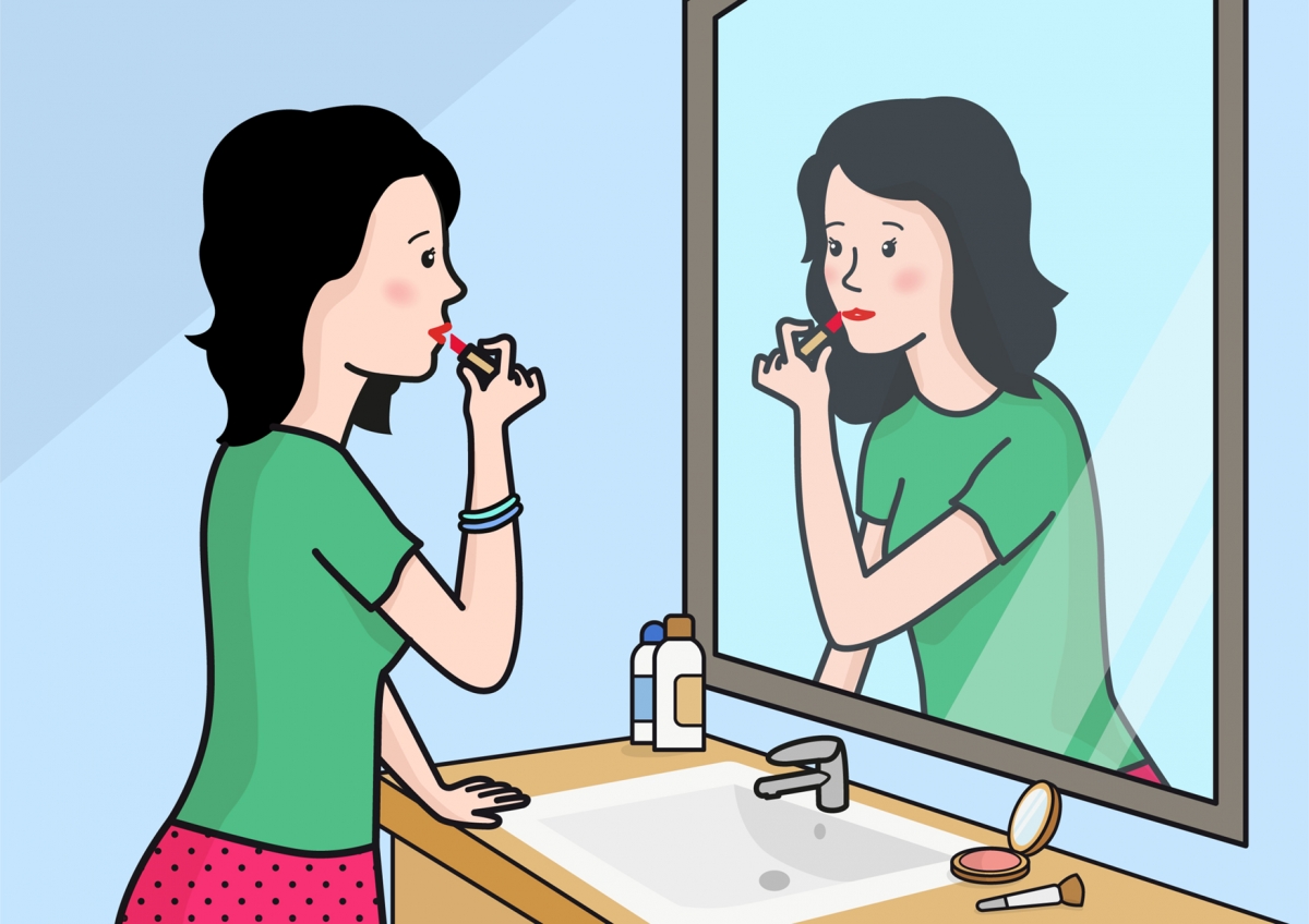 La mujer se está maquillando frente al espejo