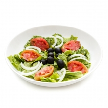 Imagen en la que se ve un plato de ensalada compuesta por lechuga, tomate, cebolla y olivas