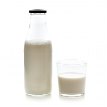 Imagen en la que puede verse una botella de cristal y un vaso a su lado con leche