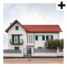 Imagen en la que se ve una casa de dos plantas y ático con una valla en el frente
