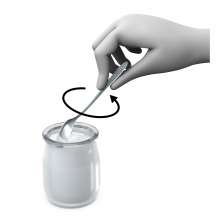 Imagen en la que se ve una mano revolviendo un yogur