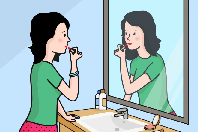 La mujer se está maquillando frente al espejo